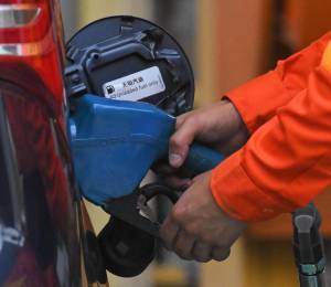 Un empleado de una gasolinera suministra combustible a un vehículo.