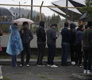 Fotografía que muestra a varios ciudadanos bajo la lluvia en el sur de Quito.