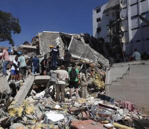 Personas trabajan en labores de rescate en una edificación colapsada por el terremoto.
