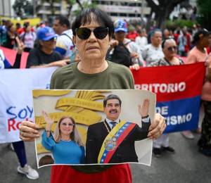 Una protestante alineada al gobierno de Nicolás Maduro, sosteniendo una foto de él junto a Cilia Flores.