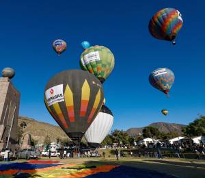 Personas observan globos aerostáticos durante la V edición del Festival de Globos este viernes, en la ciudad Mitad del Mundo, en el noroeste de Quito.
