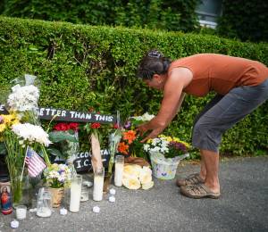 Una mujer deposita flores en un memorial improvisado en honor a un hombre que murió tras recibir disparos de agentes del Servicio de Inmigración y Control de Aduanas de EE. UU. (ICE).