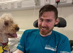 James sonriendo junto a un perro de terapia tras haber despertado del coma al que fue inducido.