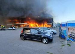 Bomberos apagando el fuego en un centro comercial afectado por un ataque con misiles rusos en la ciudad de Kremenchuk.
