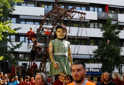 Títere gigante de una niña se mueve por las calles de Ginebra