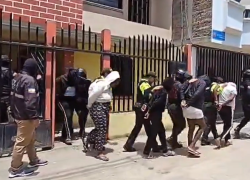 Fotografía de los detenidos siendo custodiados fuera de una vivenda.