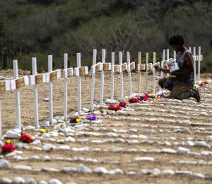 A worker paints graves for unidentified victims of the June 24 earthquake at La Esperanza Cemetery in Catia La Mar, La Guaira state, northeast of Caracas, on July 5, 2026. Venezuela's devastating twin earthquakes killed nearly 3,000, updated official figures showed on July 4, as international rescue teams began winding down search operations for survivors in the rubble of the disaster. (Photo by Miguel MEDINA / AFP)