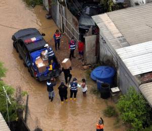 Fotografía que muestra a funcionarios del Gobierno entregando ayuda a una de las daminificadas por las lluvias en el cantón Durán.