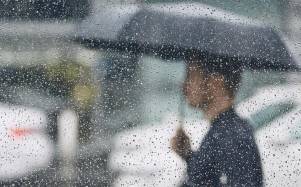 Persona debajo de la lluvia mientras se cubre con el paraguas.