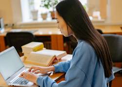 Mujer joven estudiando en su computador portátil.