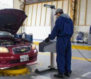 Un hombre realizando una revisión vehicular.