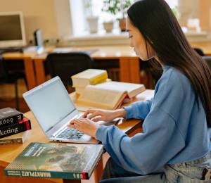 Mujer joven estudiando en su computador portátil.
