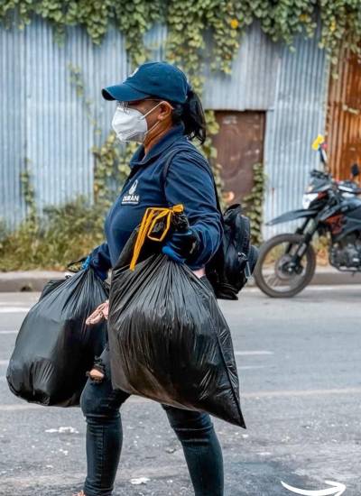 Una mujer uniformada con el distintivo del Municipio de Durán trabaja en la recolección de basura.