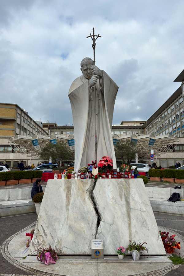 $!Velas y flores a los pies de la escultura de Juan Pablo II a las puertas del Hospital Gemelli de Roma donde permanece ingresado el papa Francisco, este miércoles.