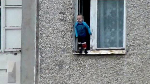 Un niño se inclina por una ventana desde el octavo piso