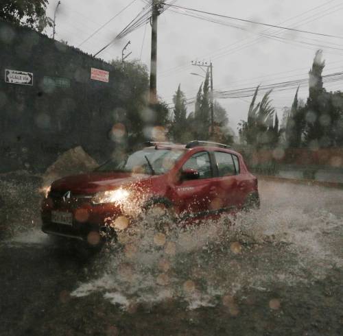 Fotografía referencial que muestra un auto atravesando un tramo inundado en la ciudad de Quito.