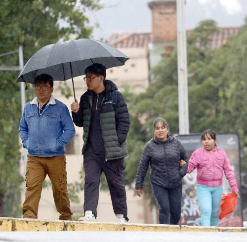 Fotografía referencial que muestra a ciudadanos con paraguas en la ciudad de Cuenca.