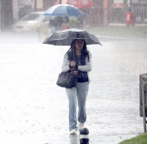 Fotografía referencial que muestra a una mujer en medio de una fuerte lluvia.