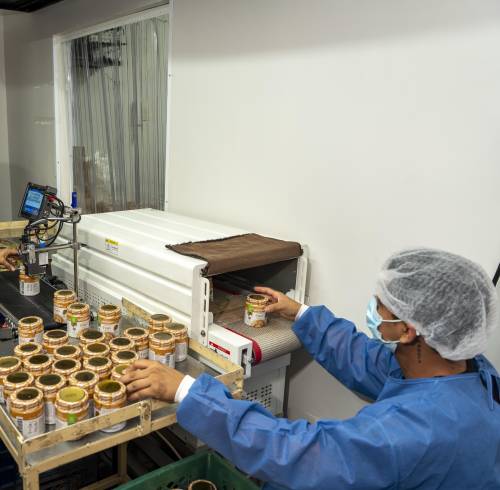 Empleados de la planta de producción de Life Choice etiquetan cremas de maní en sus envases.