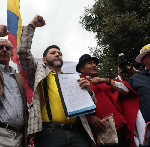 Fotografía que muestra al abogado Washington Andrade (2-I) y al dirigente indígena Leonidas Iza (3-I) frente a la sede del Consejo Nacional Electoral (CNE).