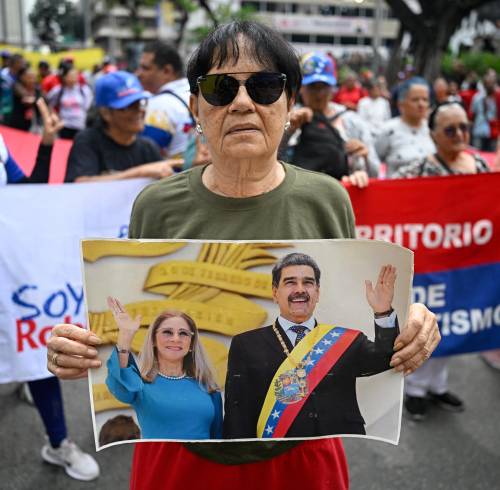 Una protestante alineada al gobierno de Nicolás Maduro, sosteniendo una foto de él junto a Cilia Flores.