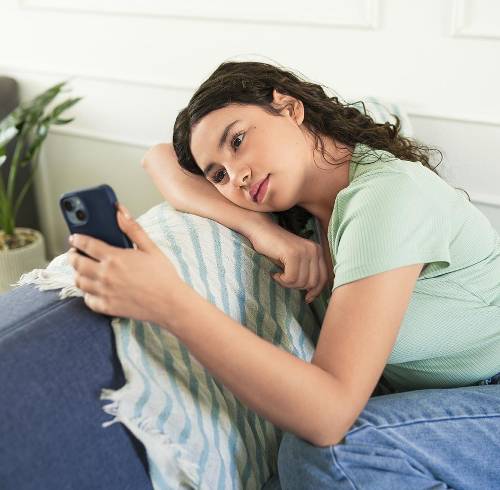 Una adolescente triste mientras usa el teléfono móvil y espera un mensaje o una respuesta de alguien.