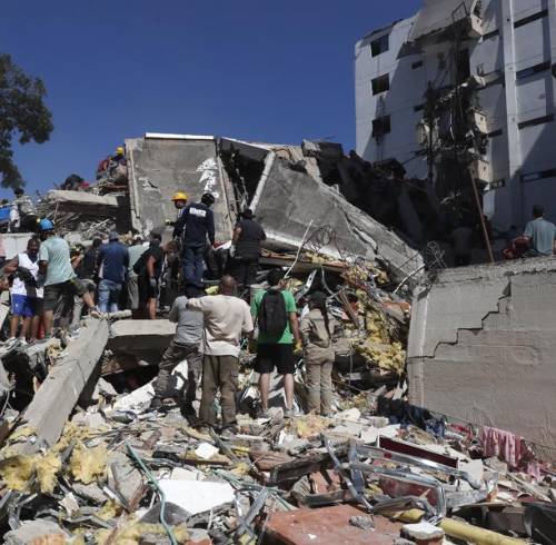 Personas trabajan en labores de rescate en una edificación colapsada por el terremoto.