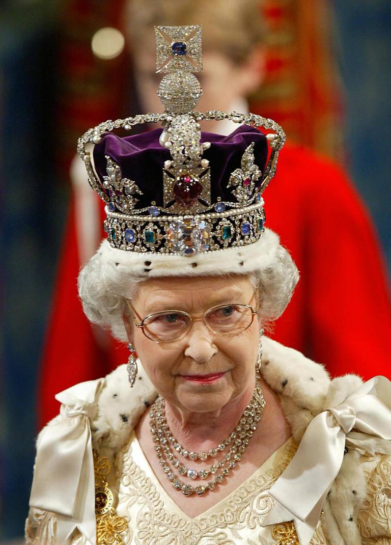 $!Foto de archivo tomada el 13 de noviembre de 2002, la reina Isabel II de Gran Bretaña, con la corona imperial, camina en procesión por la Galería Real camino a dar su discurso durante la inauguración ceremonial del Parlamento en Londres. (Photo by Adrian DENNIS / POOL / AFP)