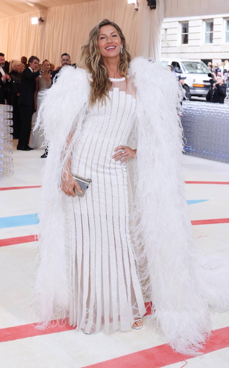 $!La modelo brasileña Gisele Bündchen rindió homenaje al diseñador con una de sus creaciones para Chanel, un vestido blanco de franjas y transparencias y una capa bordada con plumas.