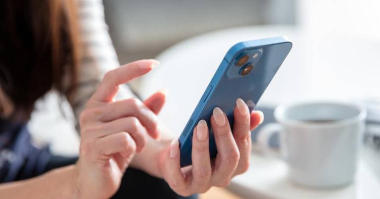 $!Una mujer revisando su celular en la sala de una casa.