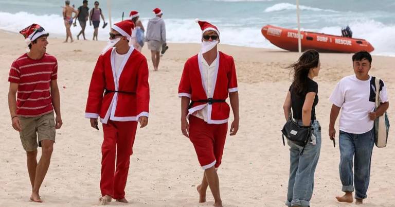 $!Personas vestidas como Papá Noel en Bondi Beach, Australia.