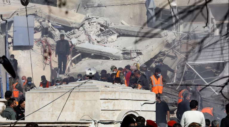 $!Varias personas y equipos de rescate se reúnen frente a un edificio destruido por un ataque en Damasco.