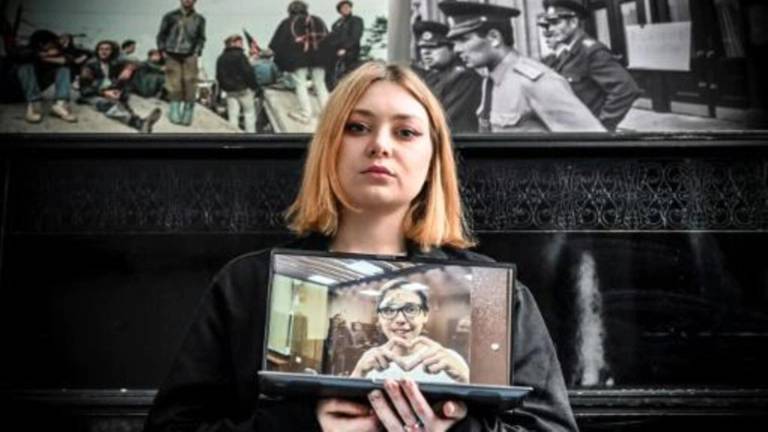 Alexandra mostrando una foto de Artiom mientras se encuentra detenido por recitar un poema en contra de la ofensiva militar en Ucrania.