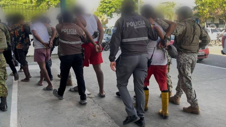 Fotografía que muestra a varios de los detenidos siendo custodiados por uniformados.