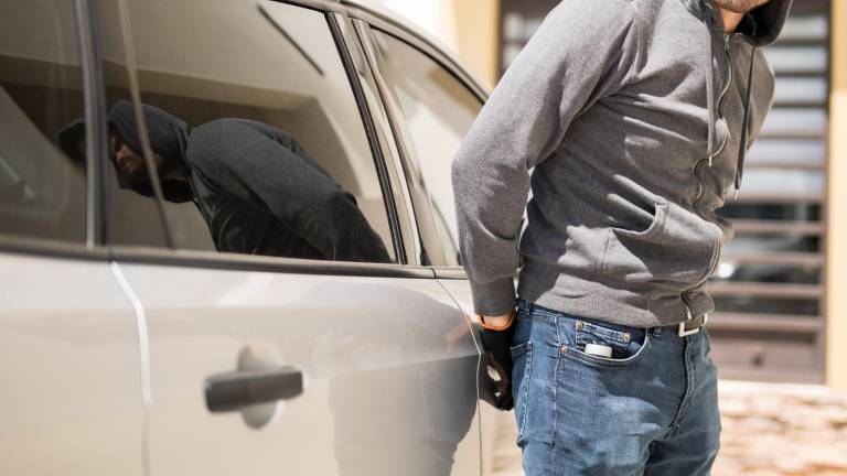 Hombre sospechoso tratando de abrir la puerta de un auto.