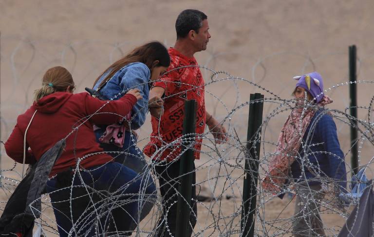 $!Migrantes cruzan una alambrada de navajas y púas, en el área fronteriza con Estados Unidos, el 29 de febrero de 2024, en Ciudad Juárez (México).
