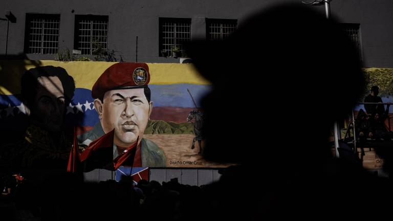 Partidarios del presidente de Venezuela, Nicolás Maduro, frente a un mural que representa al fallecido presidente Hugo Chávez.