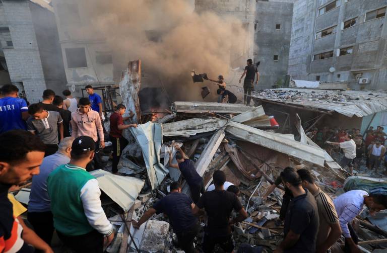 $!Palestinos buscan entre los escombros de un edificio derrumbado supervivientes tras un aparente ataque del ejército israelí en Khan Younis, en el sur de la Franja de Gaza, el 4 de noviembre de 2023 (Mahmud HAMS/AFP)