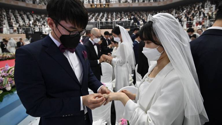 Las parejas con máscaras protectoras asisten a una ceremonia de boda masiva. Foto: AFP