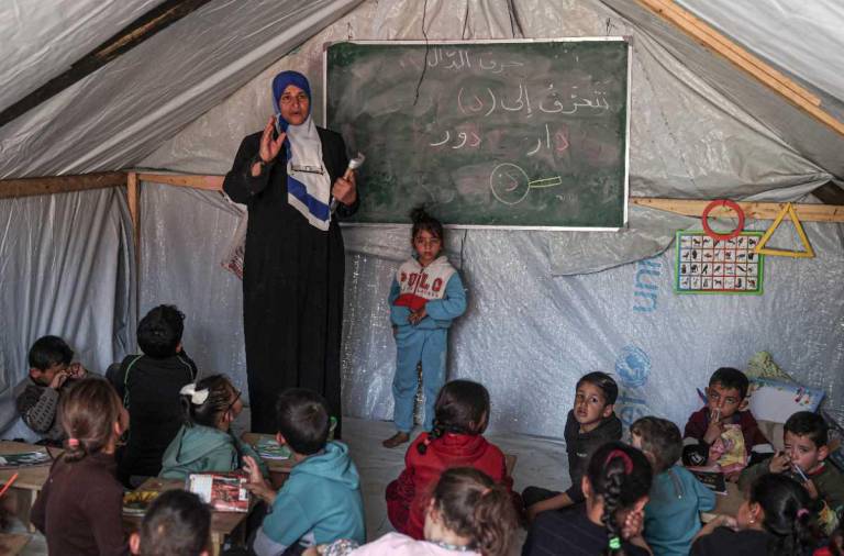 $!Maestro habla con los estudiantes en un aula improvisada en un campamento para palestinos desplazados en Rafah, en el sur de Gaza.