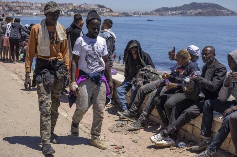$!Migrantes subsaharianos se sientan en un malecón en la ciudad norteña de Fnideq mientras intentan cruzar la frontera de Marruecos al enclave español de Ceuta.
