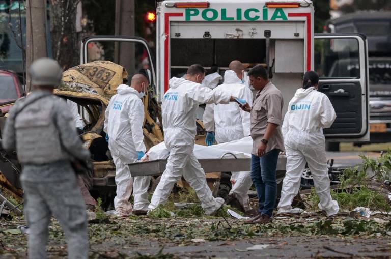 $!Agentes de policía cargan el cuerpo de una víctima de la explosión de una bomba en Cali, Colombia.
