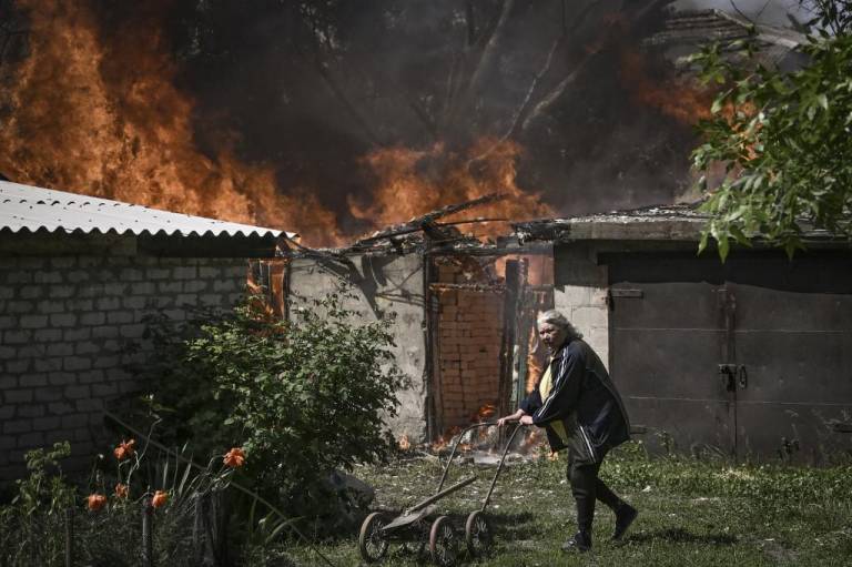 $!Una anciana se aleja del garaje de una casa en llamas después de un bombardeo en la ciudad de Lysytsansk, en la región oriental ucraniana de Donbas.