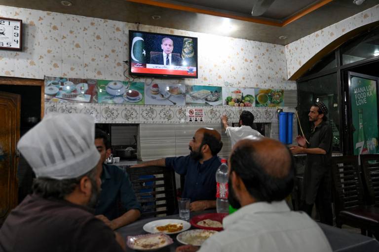 $!La gente mira la televisión en un restaurante mientras el primer ministro de Pakistán, Shehbaz Sharif, se dirige a la nación.