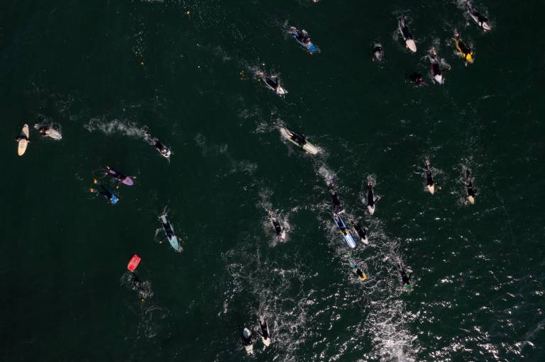 $!Vista aérea de surfistas que participan en una ceremonia en honor a dos surfistas australianos y un estadounidense que desaparecieron la semana pasada durante un viaje de surf en la playa de San Miguel.
