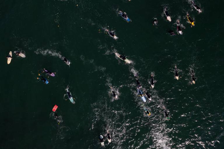 $!Vista aérea de surfistas que participan en una ceremonia en honor a dos surfistas australianos y un estadounidense que desaparecieron la semana pasada durante un viaje de surf en la playa de San Miguel.