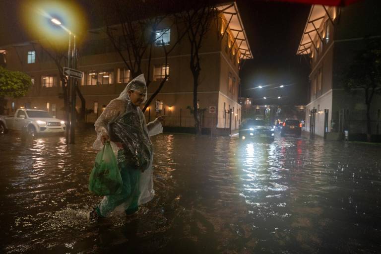 $!Una persona camina por una calle inundada debido a las fuertes lluvias, este miércoles en Samborondón.