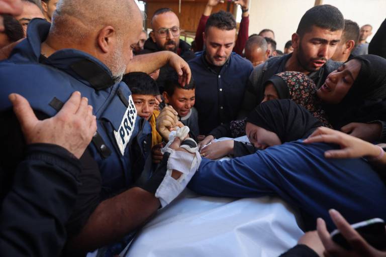 $!La esposa (D) de Hamza Wael Dahdouh, periodista de la cadena de televisión Al Jazeera, y su padre, jefe de la oficina de Al Jazeera en Gaza, Wael Al-Dahdouh (L), lloran sobre su cuerpo durante su funeral, después de que fuera asesinado en un informó sobre un ataque aéreo israelí en Rafah, en la Franja de Gaza, el 7 de enero de 2024.
