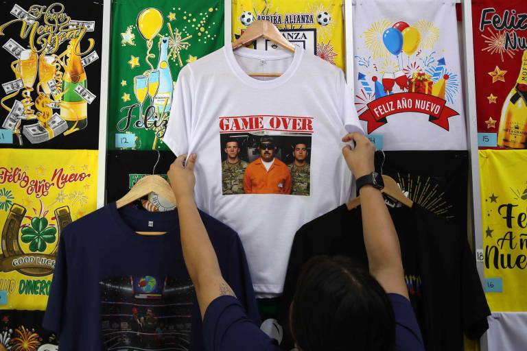 $!Una persona organiza camisetas con imágenes de la captura de Nicolás Maduro, este martes, en Lima (Perú).