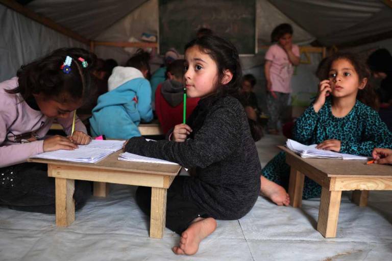 $!Los niños atentos a las clases en un aula improvisada en un campamento para palestinos desplazados en Rafah, en el sur de Gaza.